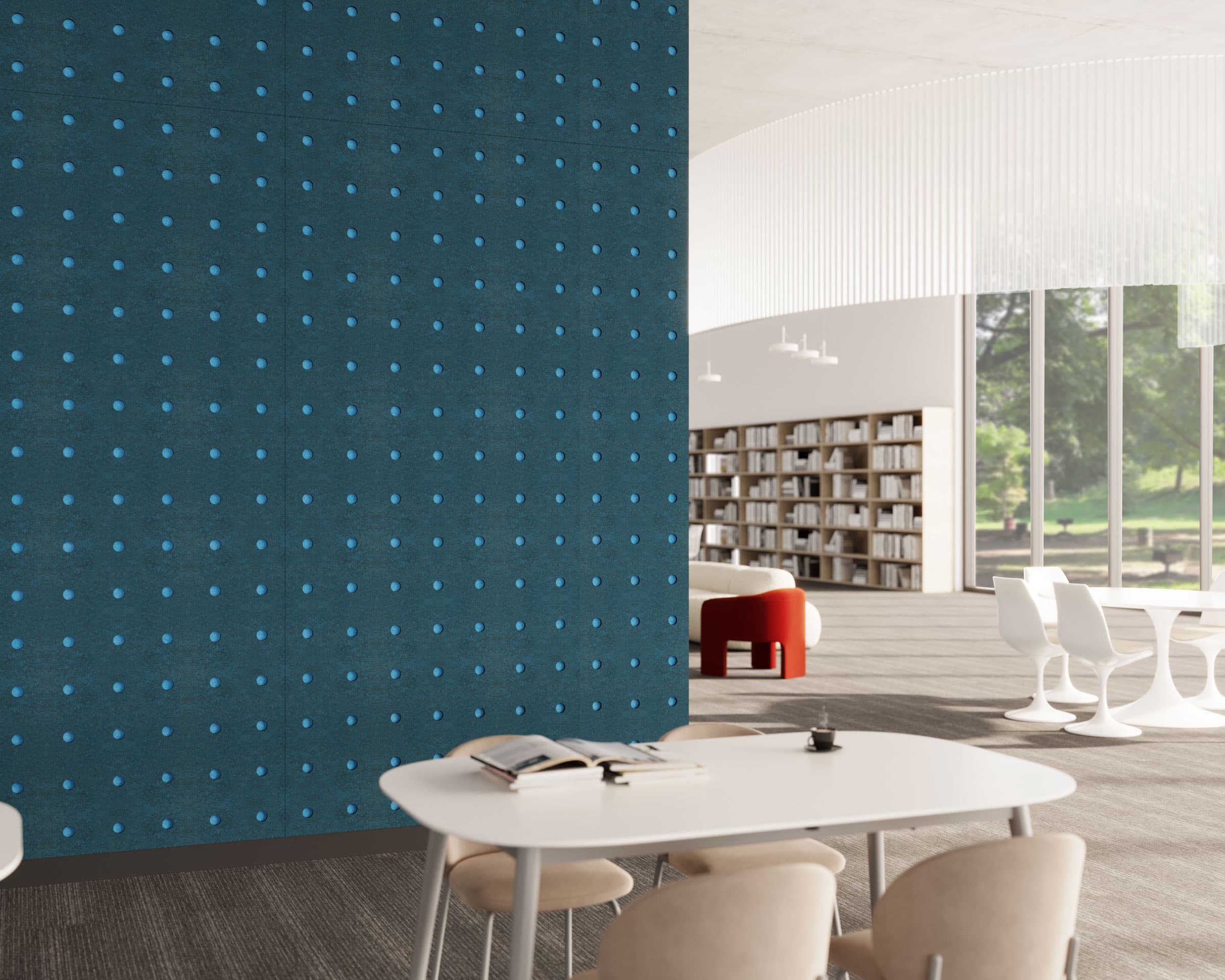 A modern, spacious library room with a blue circle acoustic felt wall panel on the left. The room features white tables and beige chairs. Sunlight streams through large windows, highlighting bookshelves and a green outdoor view in the background.