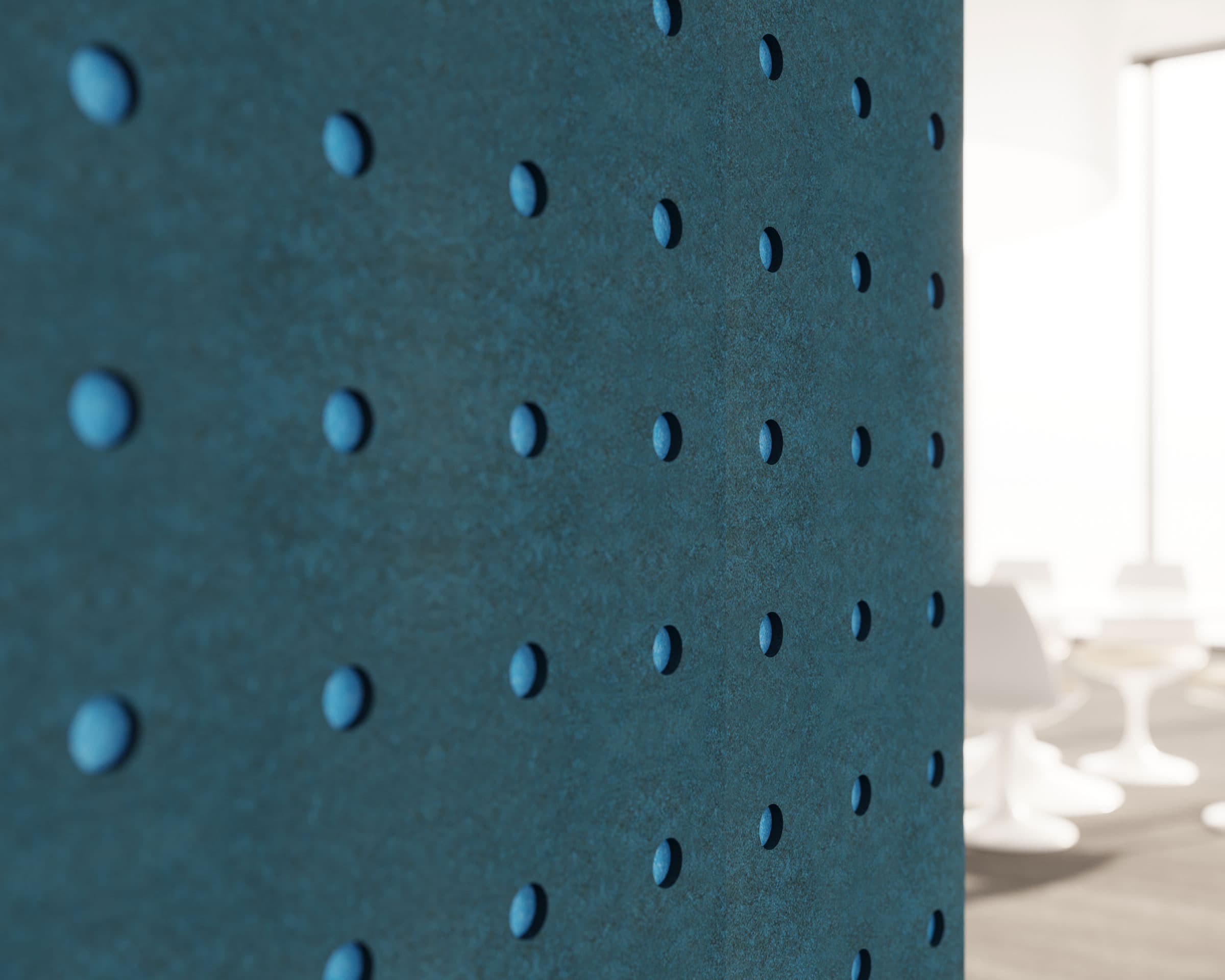Close-up of a textured blue wall featuring acoustic felt wall panels with small, evenly spaced, circle indentations. The background is blurred but suggests a contemporary indoor setting with bright light, modern white chairs, and tables.