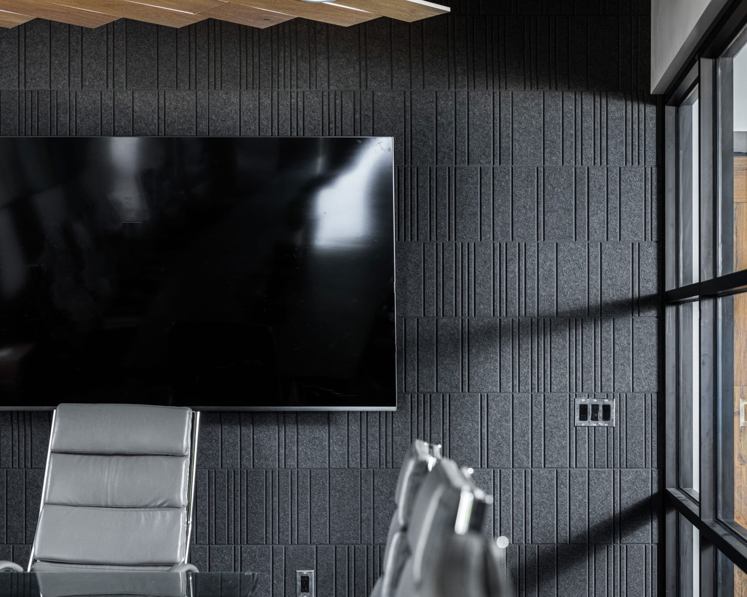 A TV on the wall surrounded by sleek acoustic felt wall tiles.