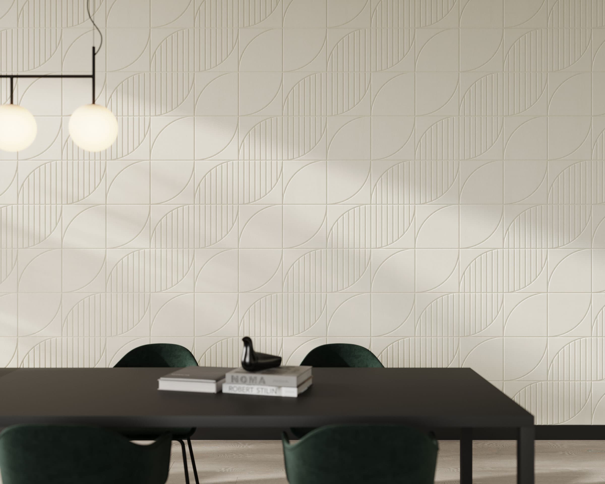 Minimalist dining area with a dark table and four dark green chairs. On the table are two stacked books and a black decorative object. The wall showcases light, textured acoustic felt wall tiles with curved lines. Two round pendant lights hang from the ceiling.