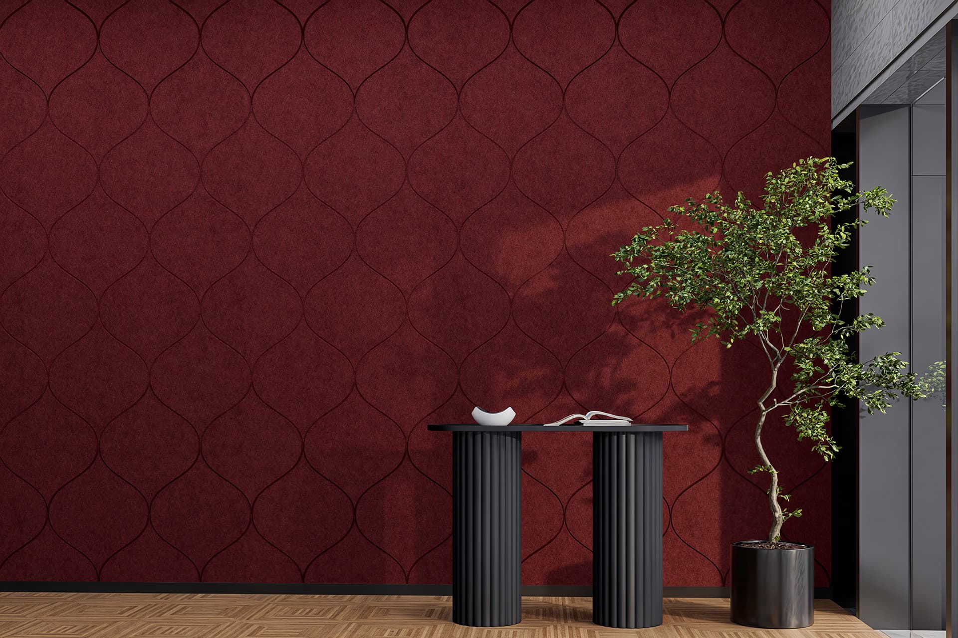 A modern interior with a deep red acoustic felt textured wall featuring a curved pattern. A sleek black console table stands against the wall, supporting an open book and decorative white bowl. To the right, a tall green potted plant adds a touch of nature.