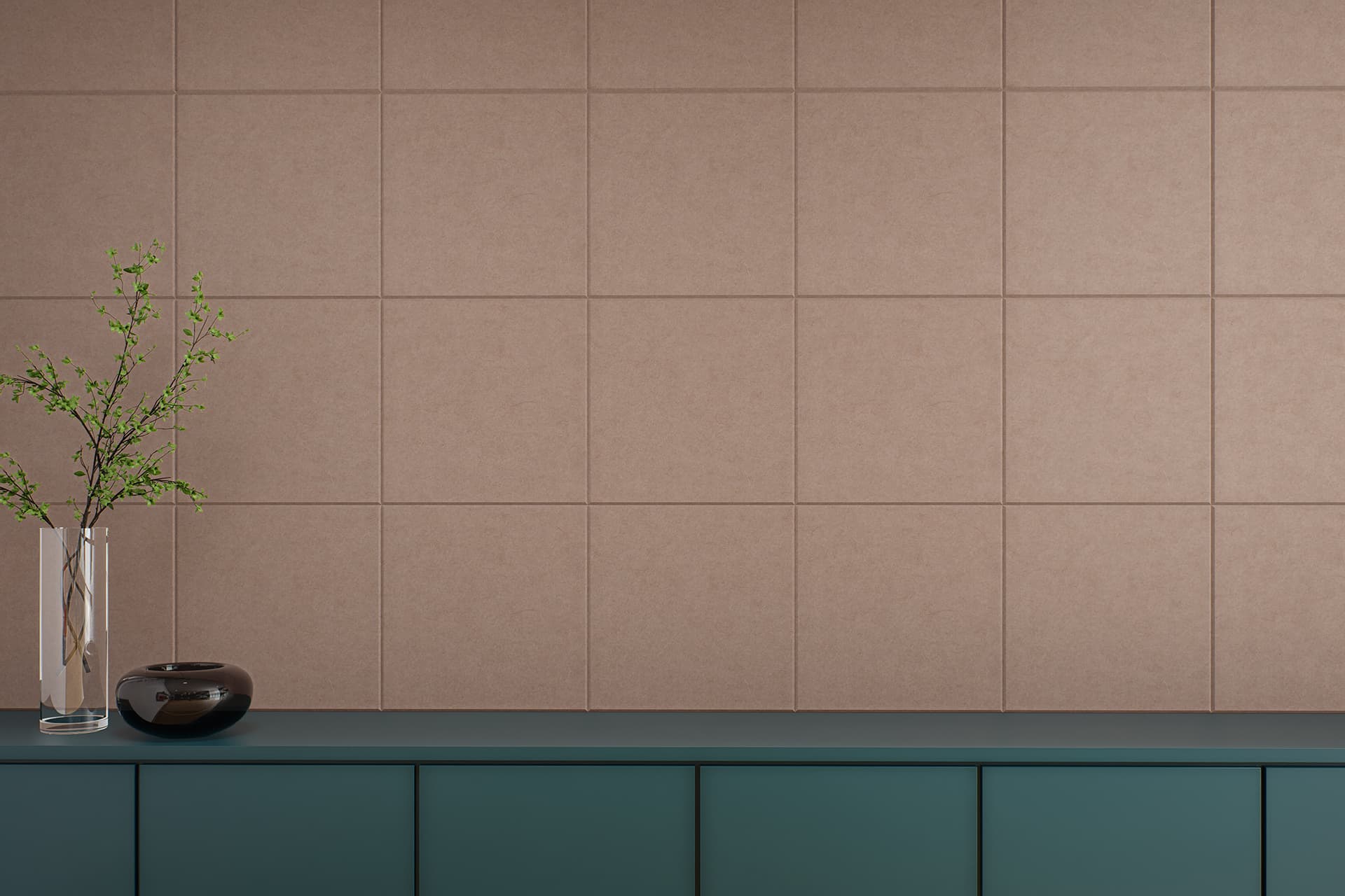 A minimalist interior features a teal cabinet against a beige-pink acoustic felt tiled wall. On the cabinet are a transparent vase holding green branches and a small, dark-colored ceramic bowl. The scene exudes simplicity and modern elegance.
