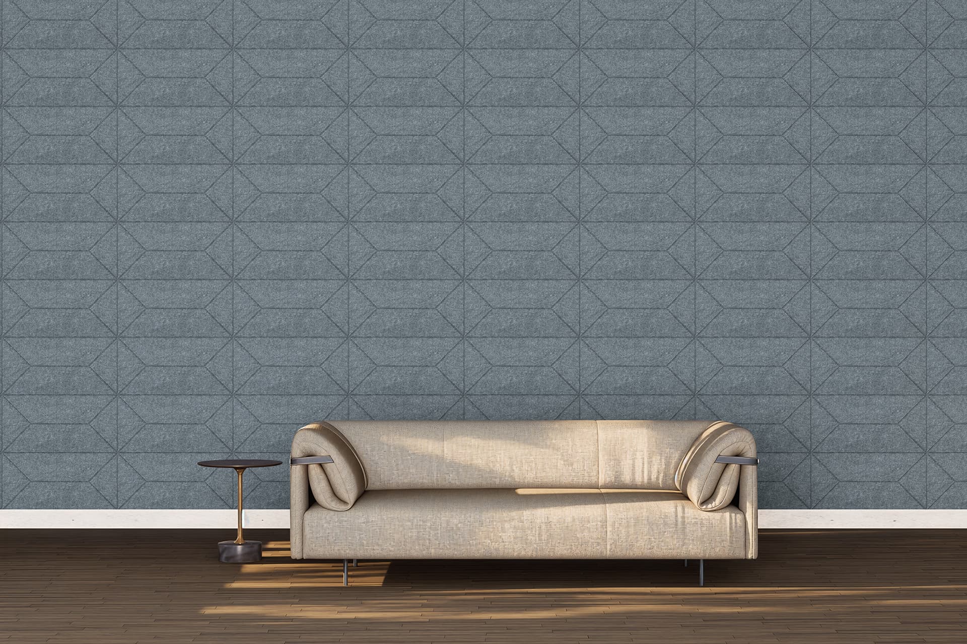 A minimalist living room features a beige sofa with cylindrical armrests, set against a gray geometric-patterned acoustic felt wall. To the left of the sofa is a small, round wooden side table. The hardwood floor complements the modern, clean aesthetic.