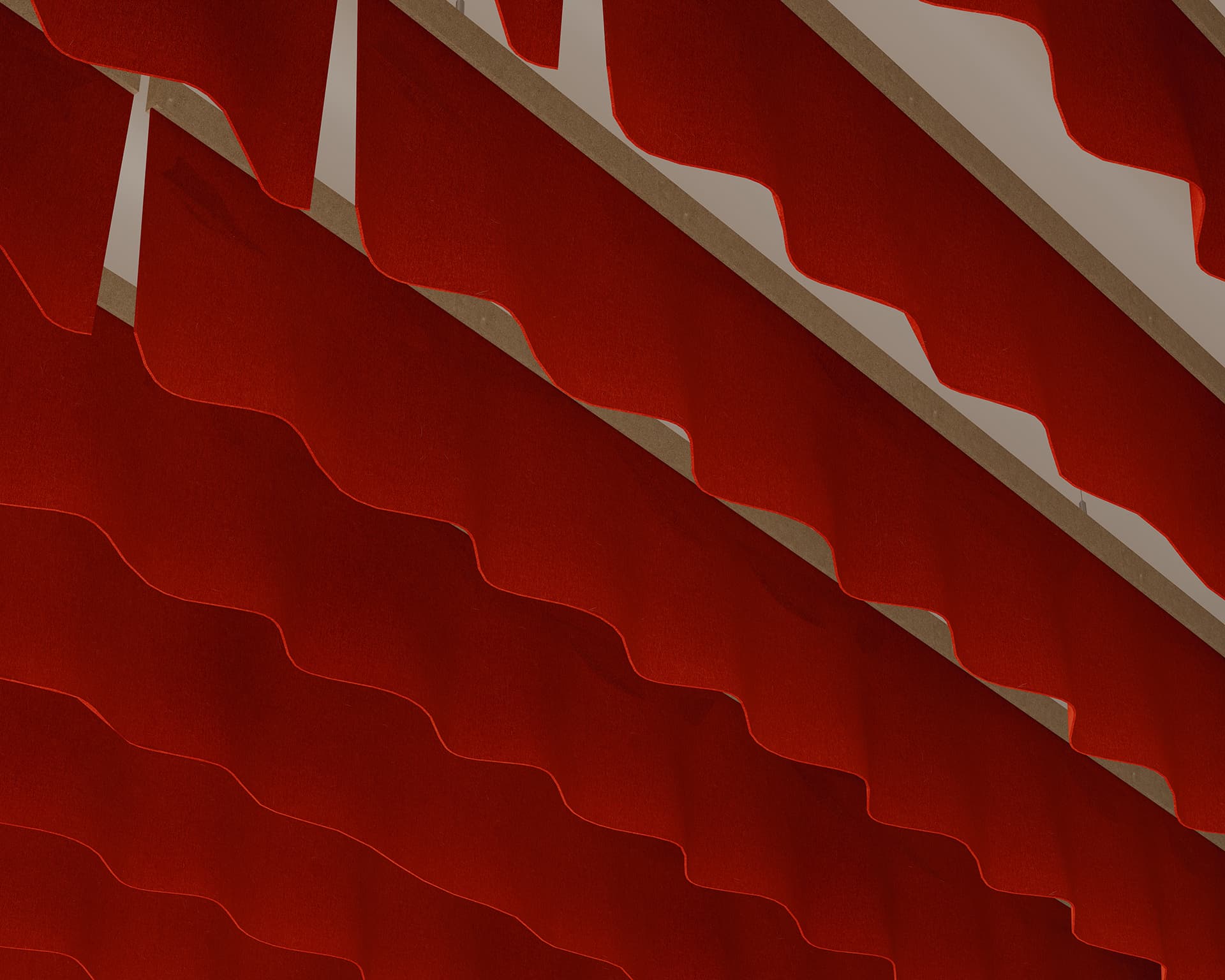 Close-up of red wave-patterned acoustic felt baffles seen from below, with the fabric overlapping in a zigzag design. A gentle breeze enhances their dynamic form, creating a geometric and symmetrical pattern.