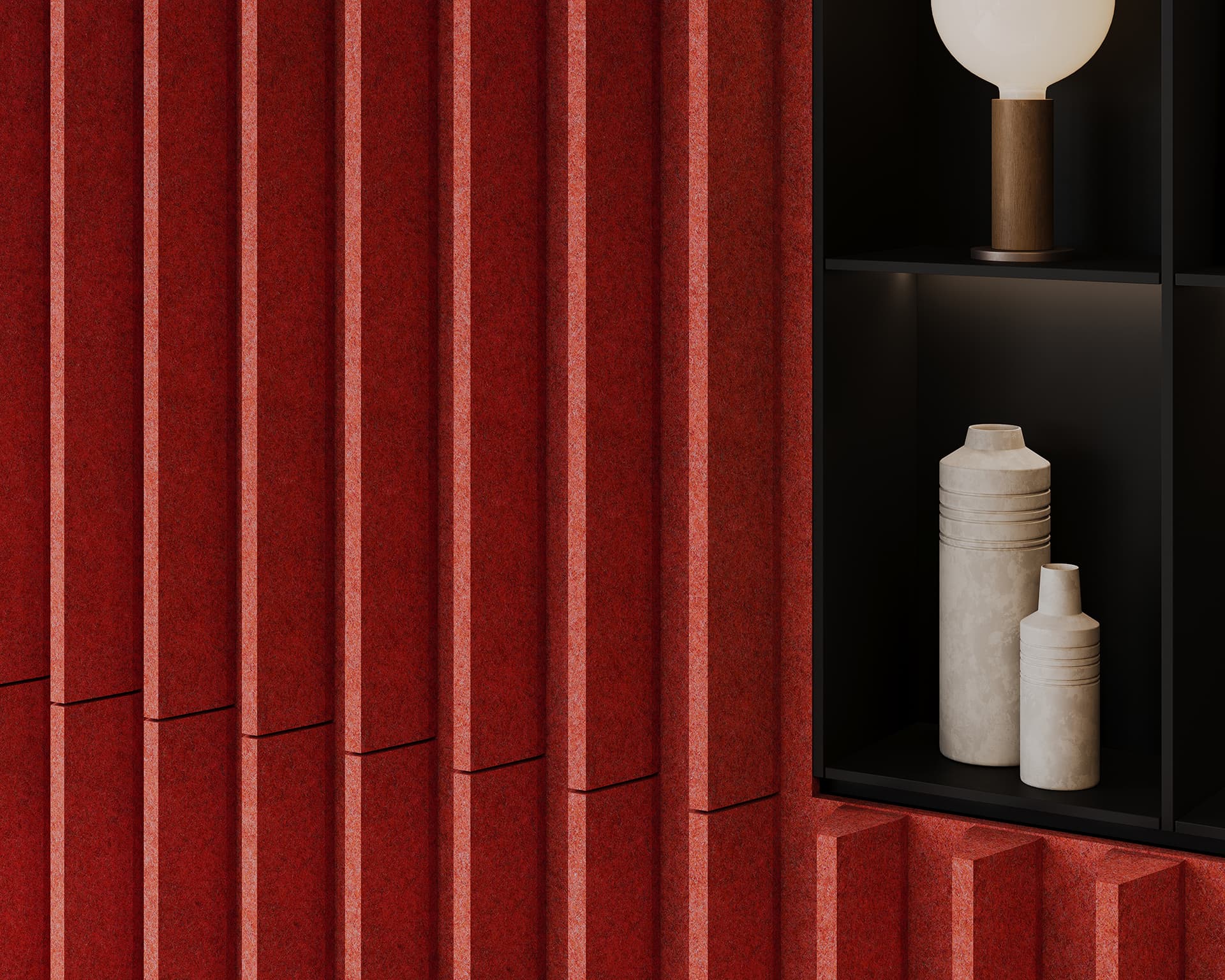 A red textured acoustic felt wall with vertical ridges on the left complements a black recessed shelf on the right, featuring a round lamp and two cement vases.