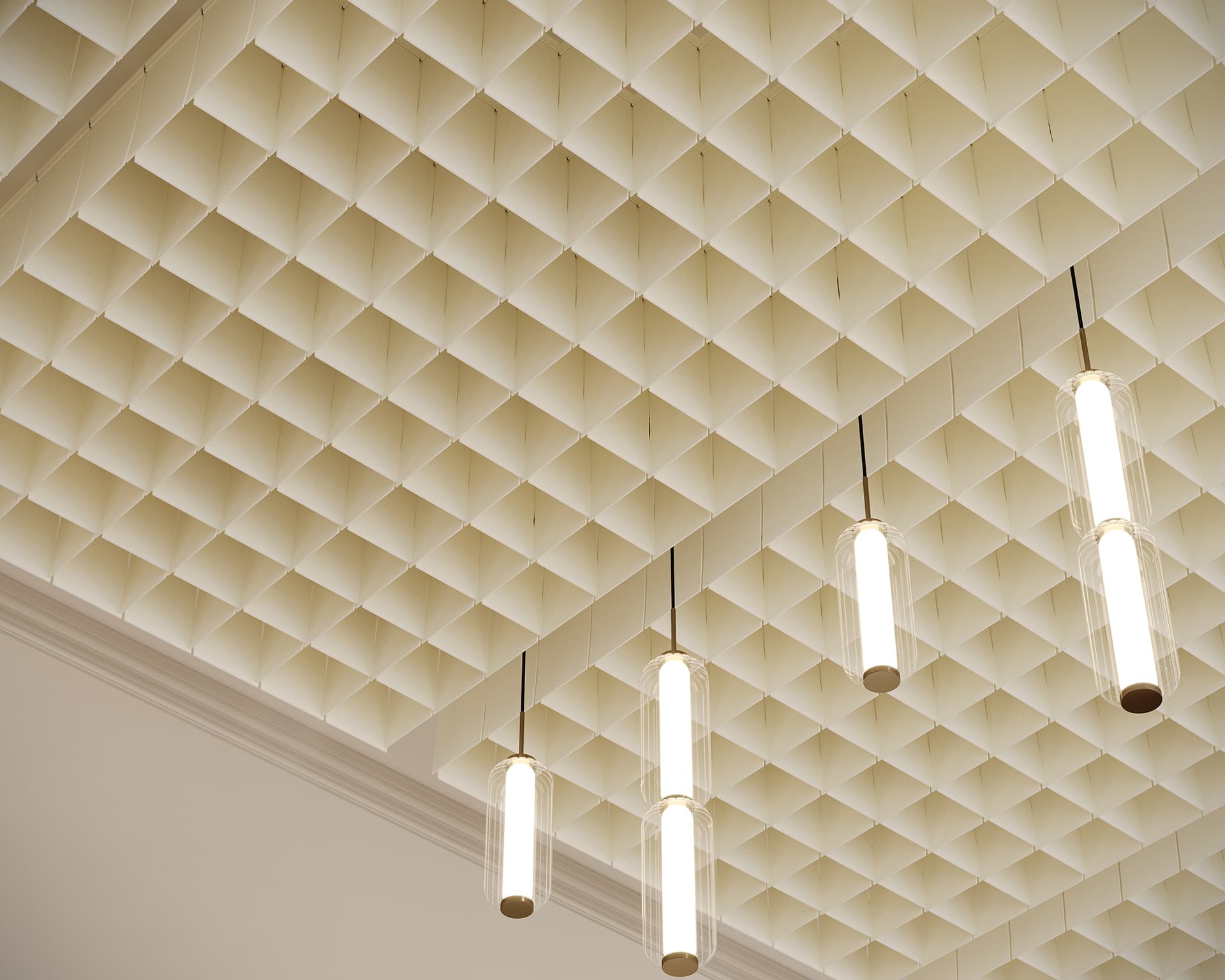A ceiling with a grid of square acoustic felt clouds, complemented by four hanging cylindrical lights, evokes a modern and structured look. The floating naturals of acoustic felt clouds enhance the minimalistic design.