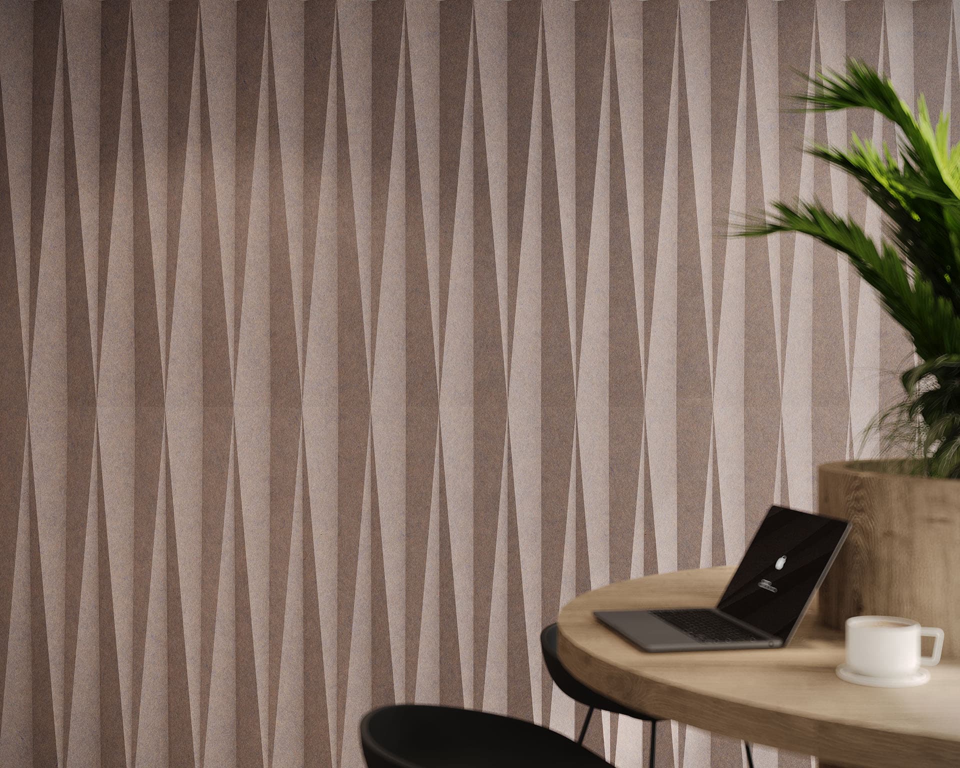 A modern workspace features a round wooden table with an open laptop, a white mug, and a plant. The background showcases dart-patterned acoustic felt wall tiles in shades of brown, creating a stylish and minimalistic atmosphere.