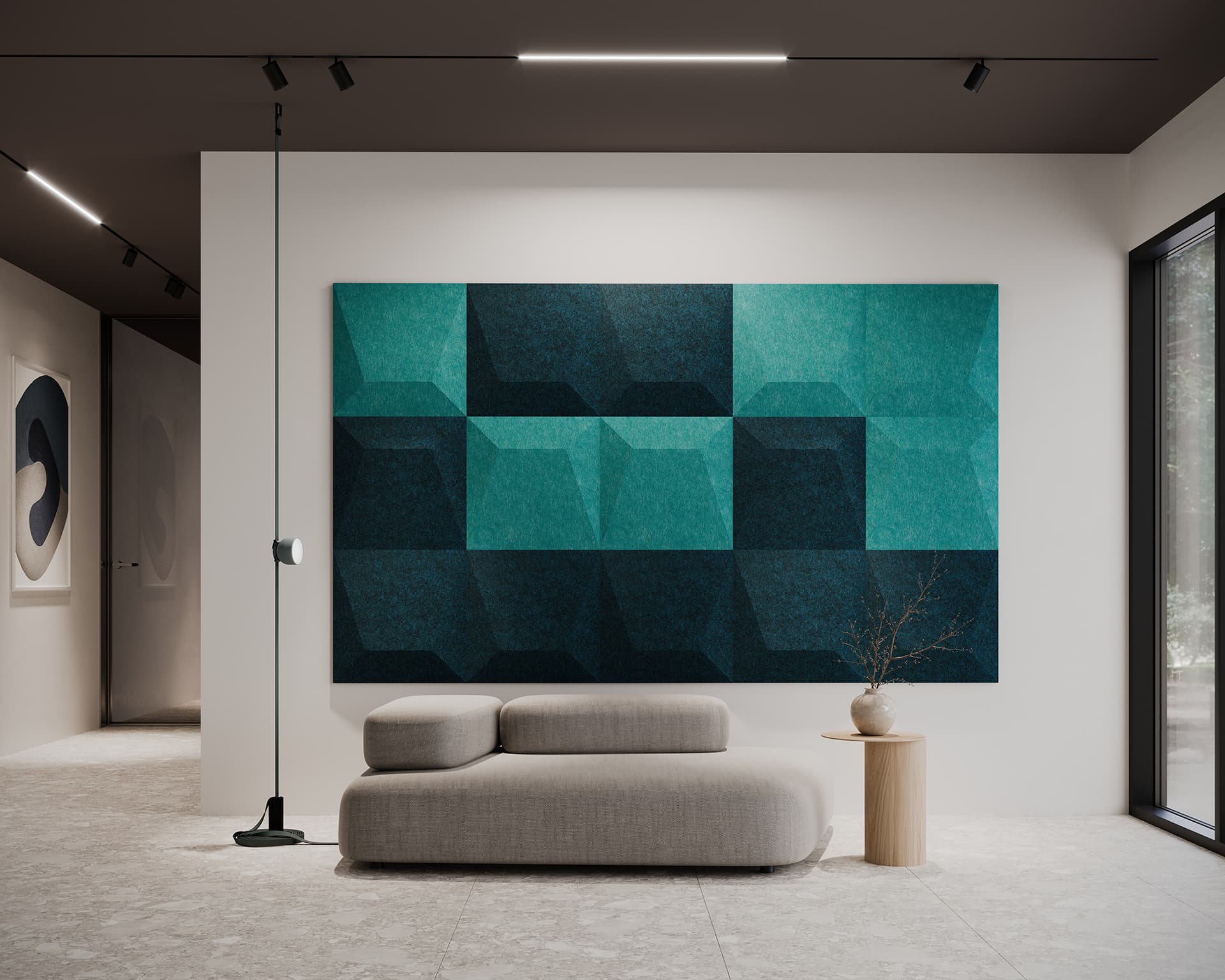 The modern interior showcases a large geometric teal and dark blue acoustic felt wall tiles. A minimalistic gray sofa and small wooden side table with a vase sit in the foreground, while the room's neutral tones bask in abundant natural light from a large window.